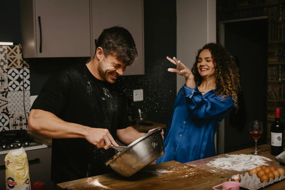 Anru mixing a bowl of flour in the kitchen while Leane dances beside him