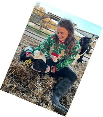 Leane crouching in a field with a lamb